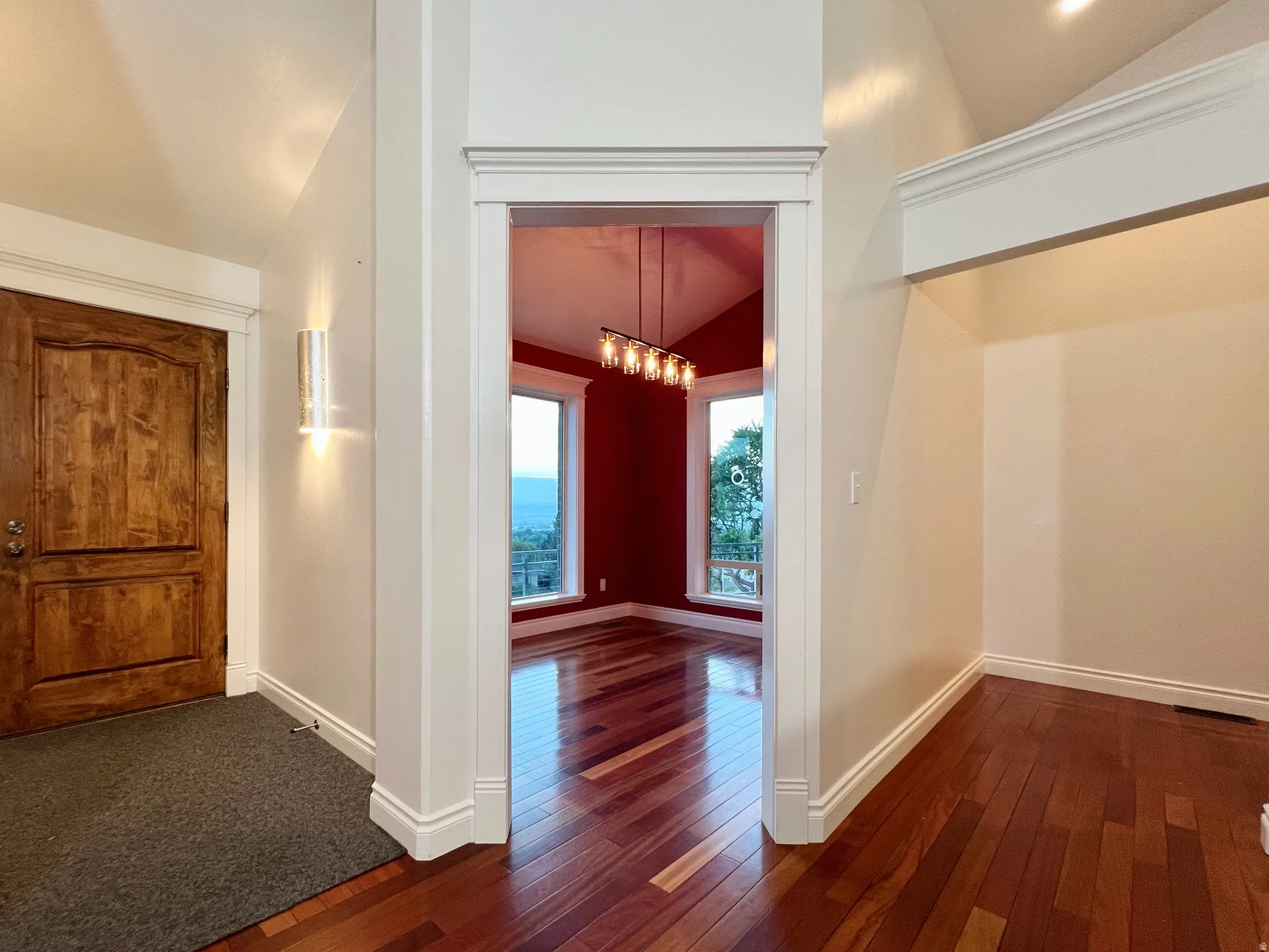 Rich wood-finish flooring extends through the entry and into the interior space, complemented by a solid wood entry door