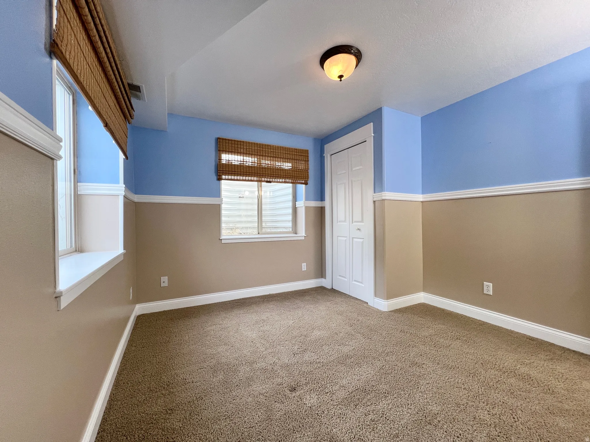 Carpeted room with a two-tone wall finish, featuring white trim and baseboards