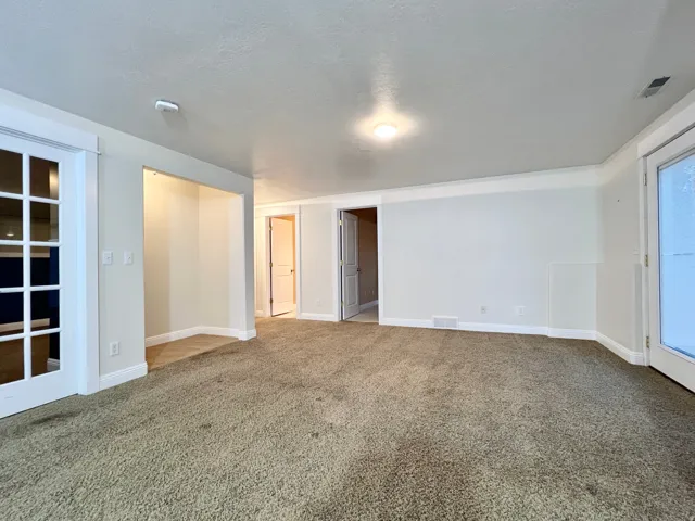 Spacious room featuring neutral carpet flooring, crisp white walls, and bright overhead lighting