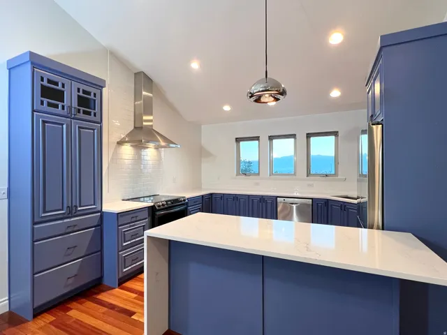 Kitchen featuring blue cabinetry with white countertops, stainless steel appliances, and a subway tile backsplash