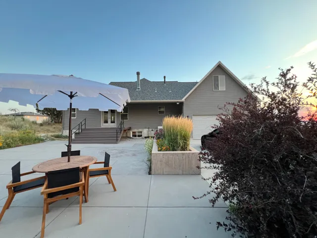 Rear exterior featuring a concrete patio, multi-level deck with black railings, and a built-in planter box with landscaping