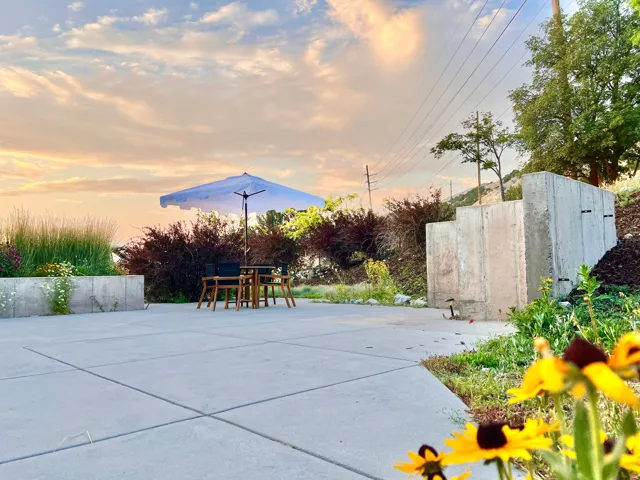Expansive concrete patio area with integrated planter boxes and terraced concrete retaining walls, complemented by mature landscaping