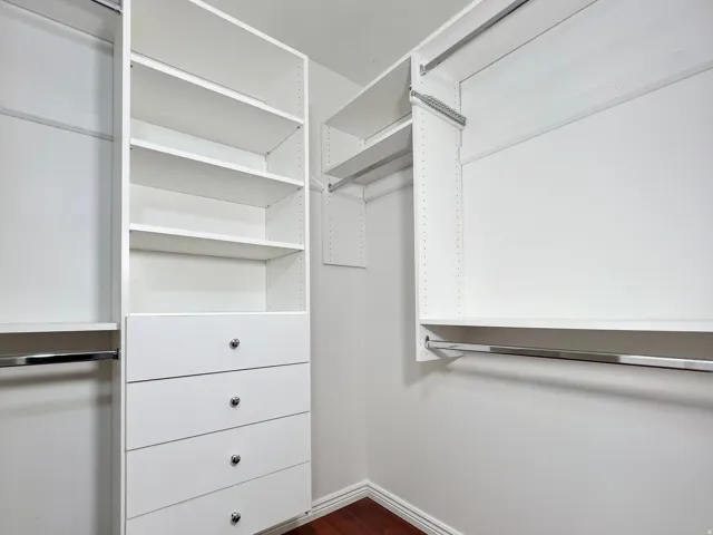 Custom closet system featuring white built-in shelving, multiple drawers with polished chrome hardware, and dedicated hanging rods