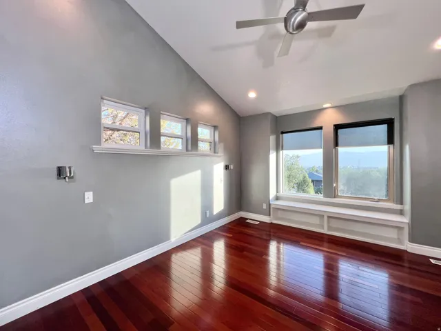 Vaulted ceiling room featuring rich wood-finish flooring