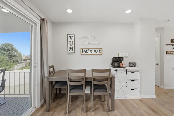 Dining area featuring wood-finish flooring, recessed lighting, and a sliding glass door opening to an outdoor deck with metal railings