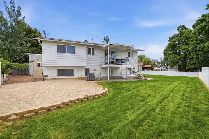 Spacious backyard featuring a large grass area, a dedicated gravel section, and a white privacy fence