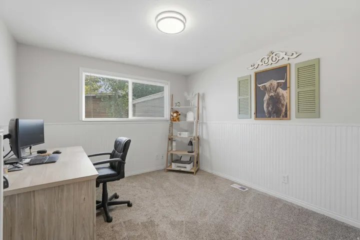 Room featuring a single window, white beadboard wainscoting, and neutral-toned carpeting