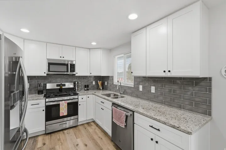 Kitchen featuring white shaker-style cabinetry, granite countertops, and a gray subway tile backsplash