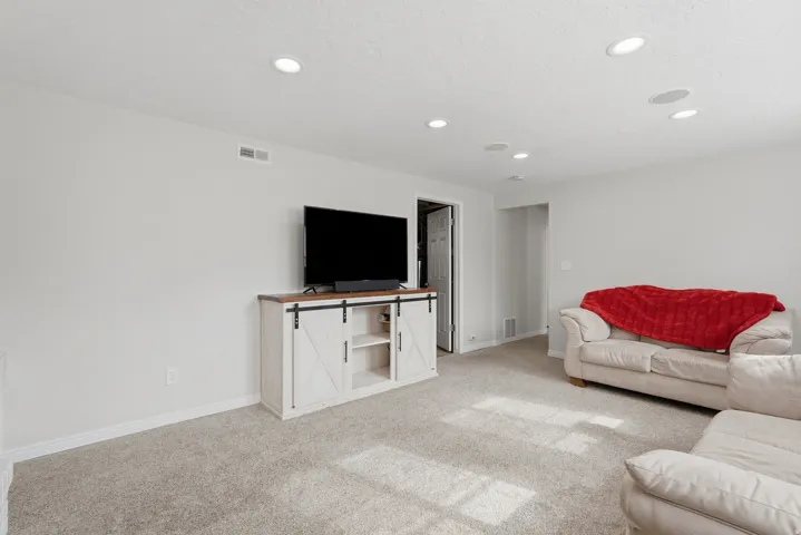 Spacious room featuring light gray carpeting, recessed ceiling lighting, and a neutral wall color