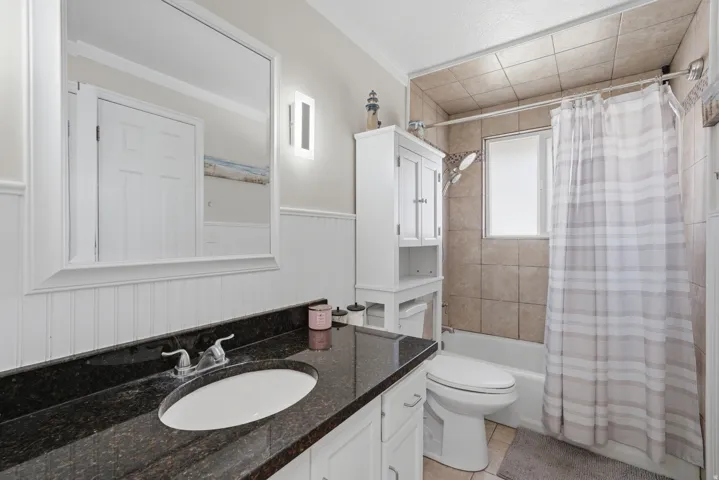 Bathroom featuring a dark speckled countertop, white undermount sink, and wainscoting