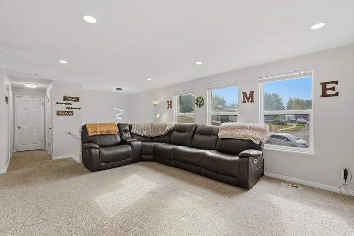Carpeted living area featuring recessed lighting and multiple windows