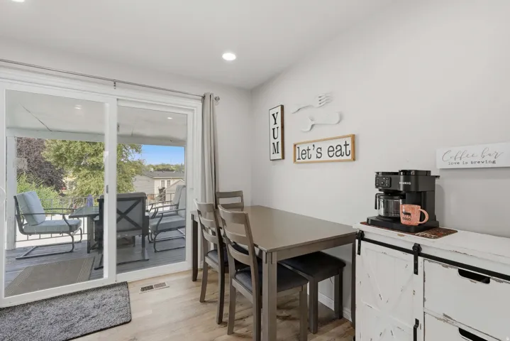 Light-filled dining area featuring wood-finish flooring, recessed lighting, and a sliding glass door providing direct access to an outdoor deck