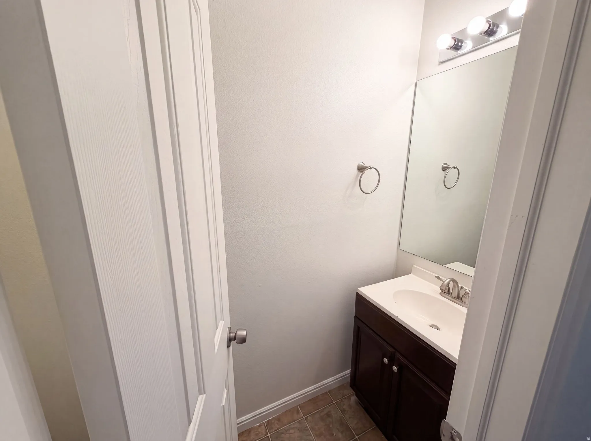 Compact powder room featuring a single vanity with a white countertop and undermount sink