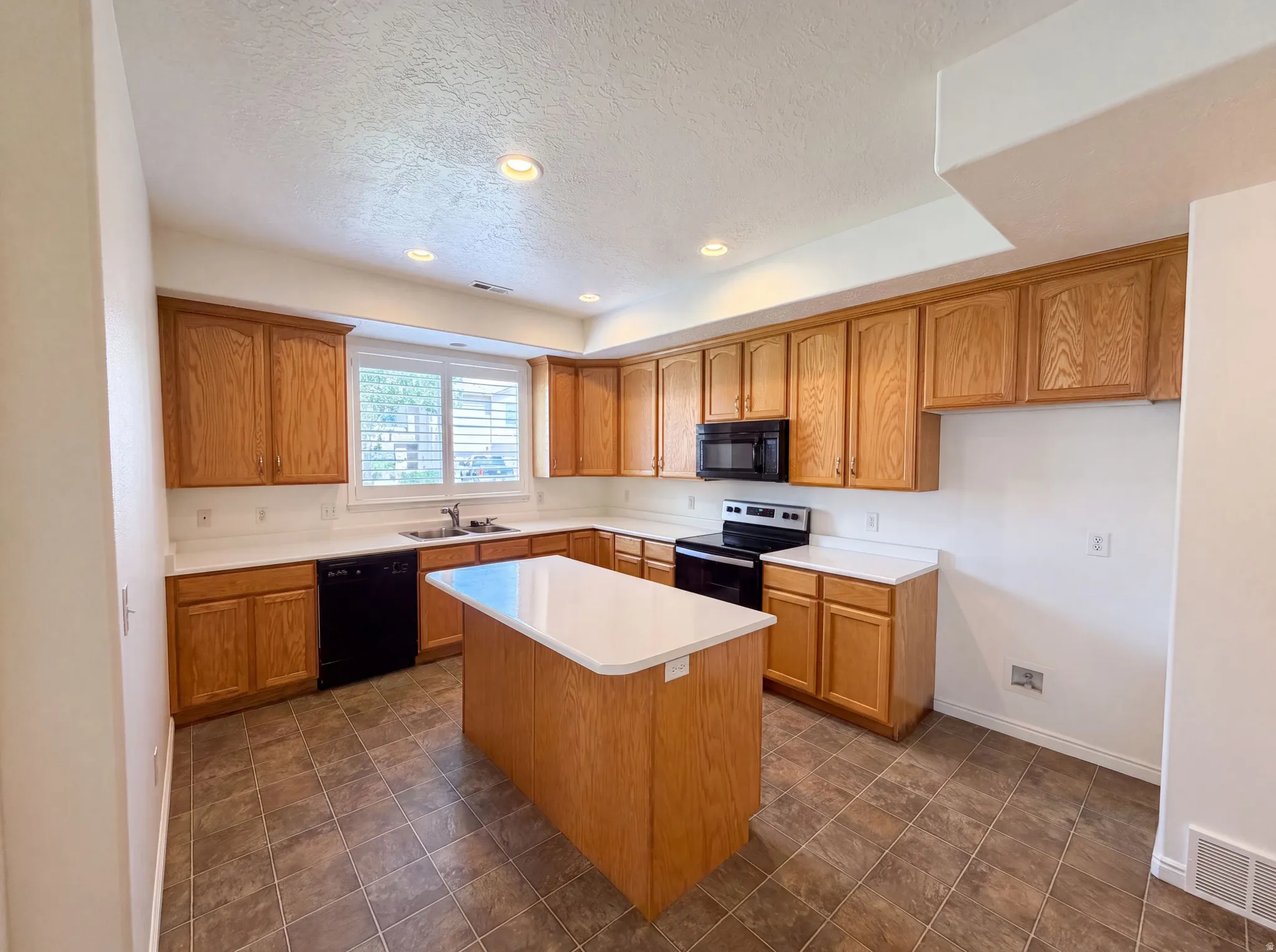 Kitchen featuring light wood cabinetry, white countertops, a center island, recessed lighting, and tile flooring