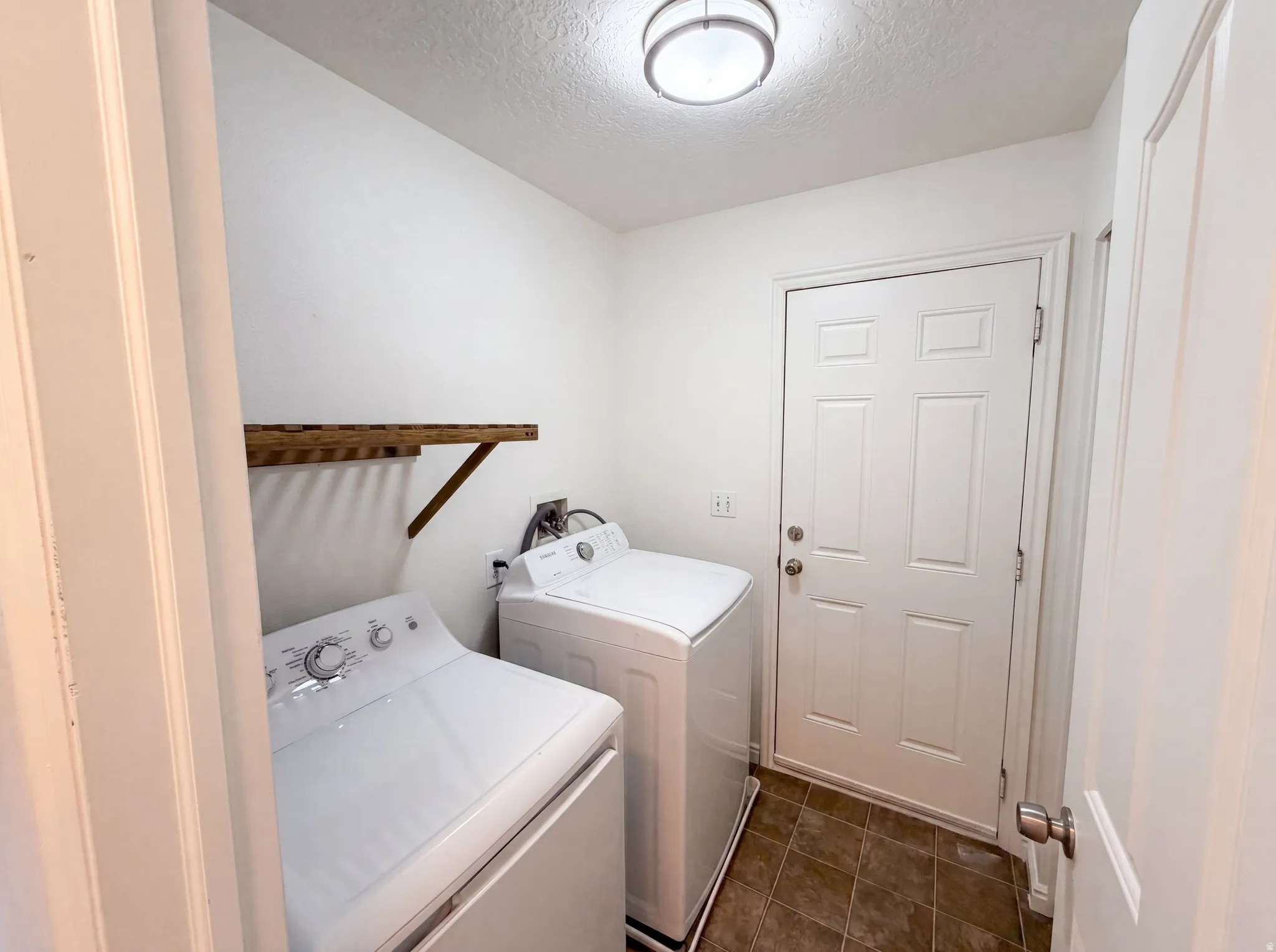 Dedicated utility space featuring a built-in wood-finish drying rack, tiled flooring, and a flush-mount ceiling light fixture