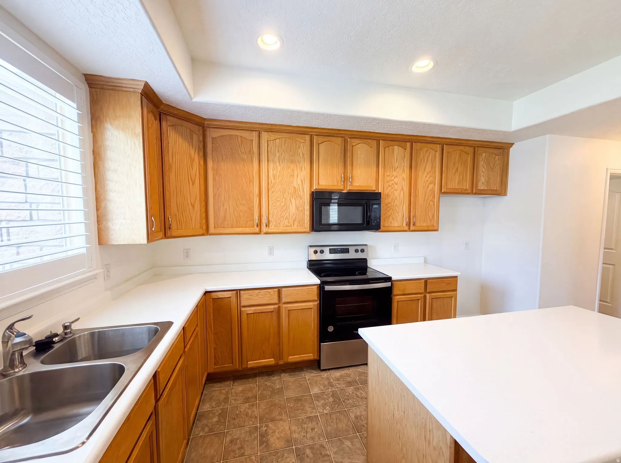 Kitchen featuring light-tone wood cabinetry, white countertops, and a dual-basin stainless steel sink