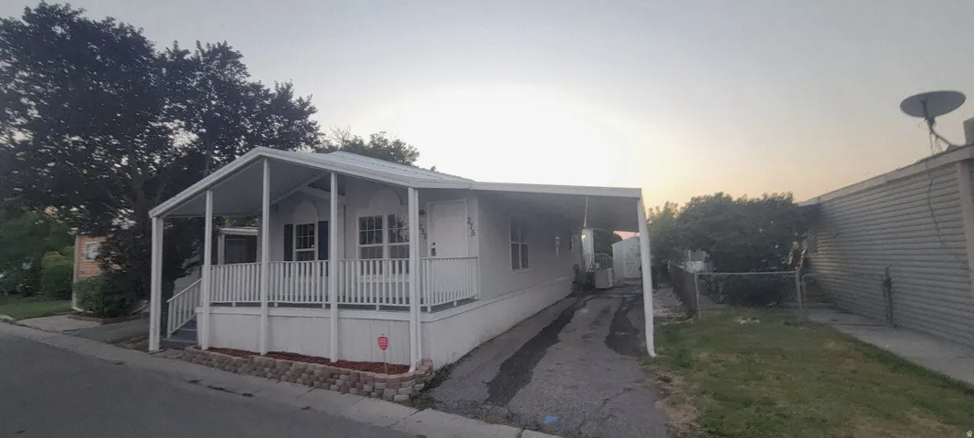 White siding exterior with a front porch, carport, and paved driveway