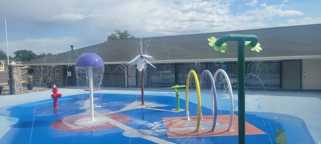 Vibrant splash pad featuring multiple water features, a colorful soft-surface base, and various water jets