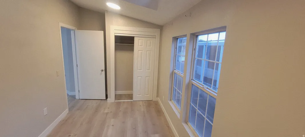 Room featuring wood-finish flooring, a vaulted ceiling, and recessed lighting