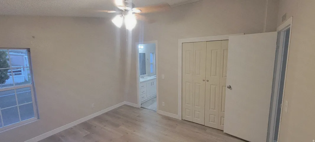 Room featuring wood-finish flooring, a ceiling fan with integrated lighting, and a double-door closet