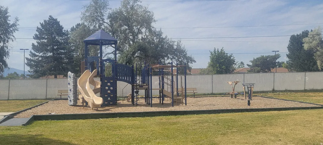 Recreational area featuring a multi-level playground structure with slides, climbing walls, and an overhead canopy