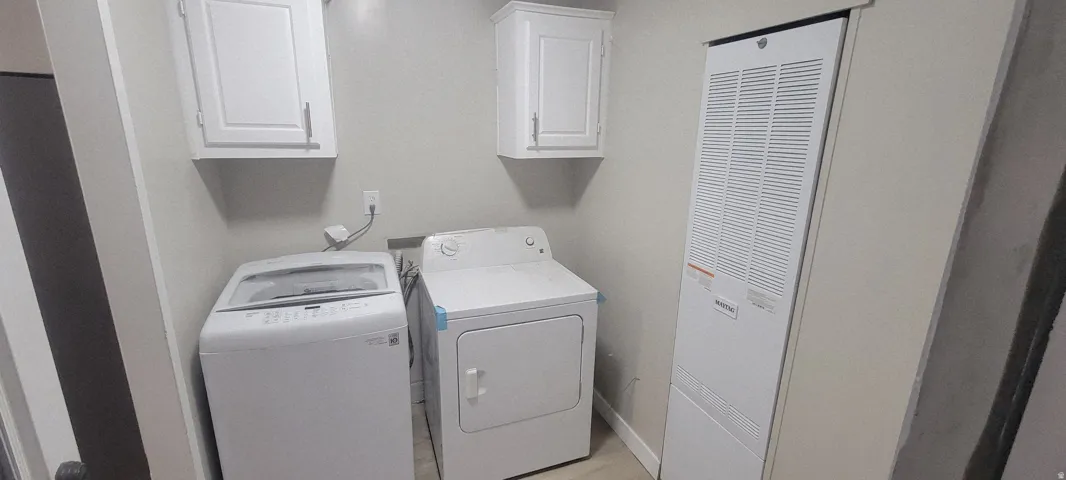 Dedicated laundry area featuring white shaker-style wall cabinets and light-toned walls