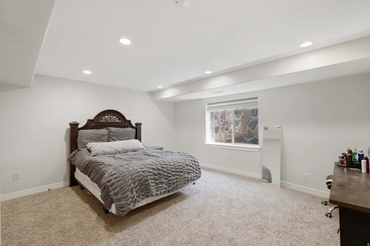 Recessed lighting, light-toned carpeting, window with stone-finish exterior, and white interior walls