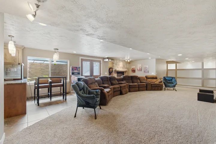 Home Theater Spacious entertainment area with carpeted flooring, built-in wet bar, stone fireplace, and integrated recessed lighting