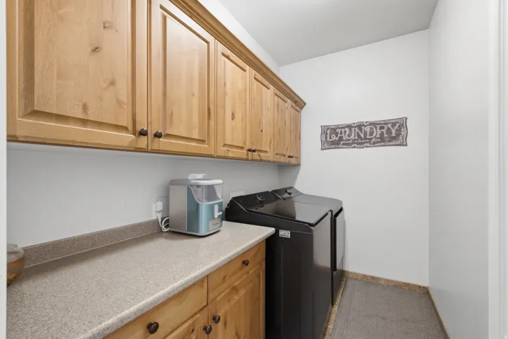 Built-in wooden cabinetry with dark hardware, light-toned countertops, and light tile flooring