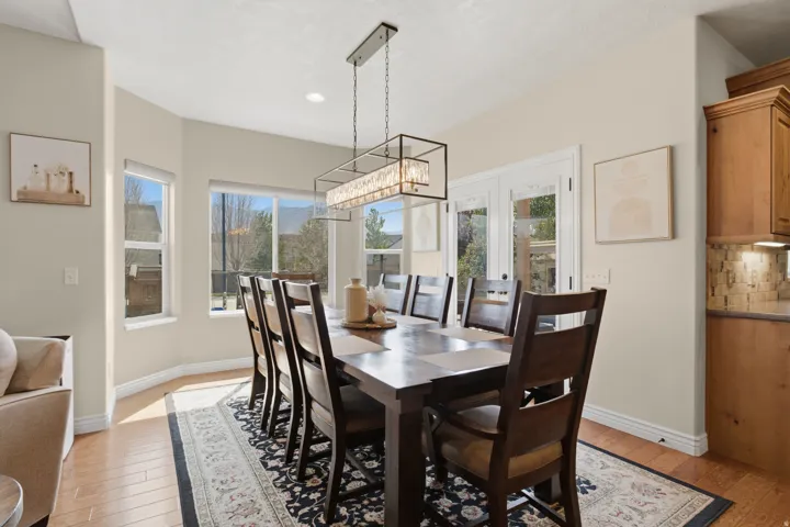 Recessed bay window, French doors, wood-finish flooring, custom wood cabinetry, and a decorative tile backsplash