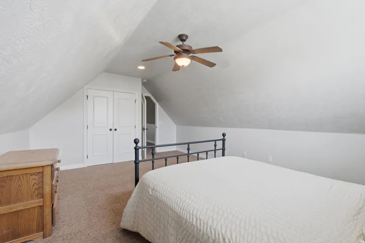 Sloped ceiling room featuring carpet flooring, bi-fold closet doors, a ceiling fan, and recessed lighting