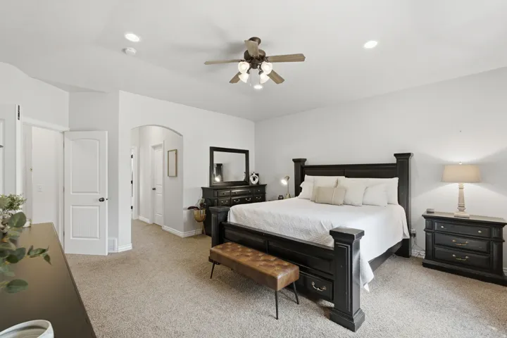 Neutral wall color, recessed lighting, ceiling fan, arched doorway, and carpet flooring