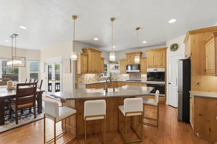 Kitchen featuring wood cabinetry, a center island with countertop seating, stone countertops, stainless steel appliances, and wood-finish flooring