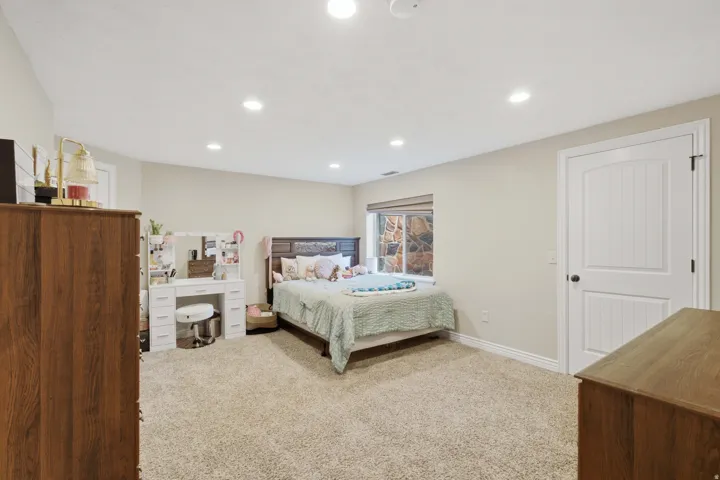 Carpeted flooring, recessed lighting, white interior door with dark hardware, window with stone exterior, and neutral wall color