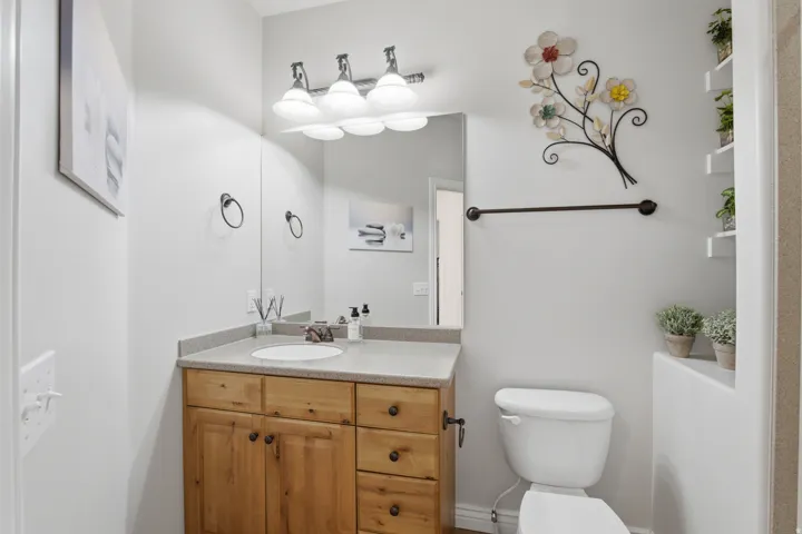 Vanity with wood-finish cabinetry, integrated sink, and stone-finish countertop