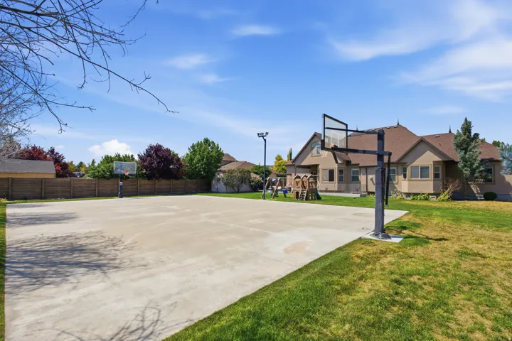 Expansive concrete sports court with two basketball hoops, bordered by a wooden fence