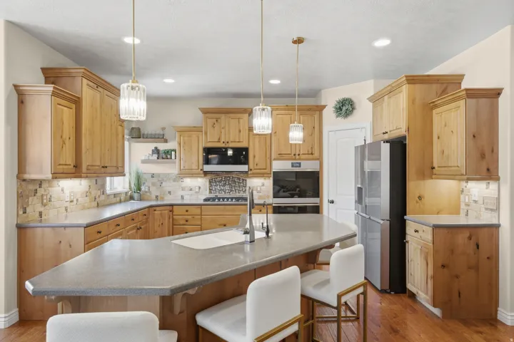 Kitchen featuring wood cabinetry, stone-finish countertops, stainless steel appliances, and a tiled backsplash