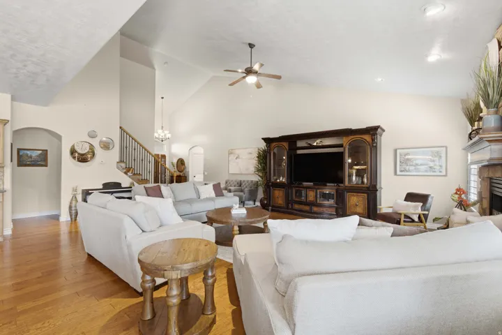 Vaulted ceilings, wood-finish flooring, staircase with metal balusters, arched doorway, and recessed lighting