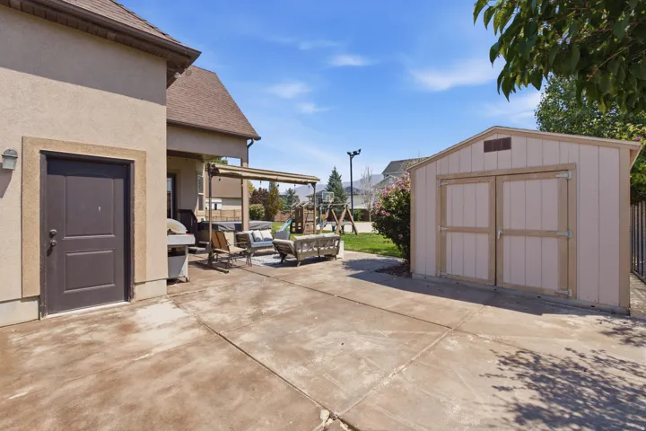 Concrete patio with a covered outdoor area, stucco exterior, and a detached storage shed
