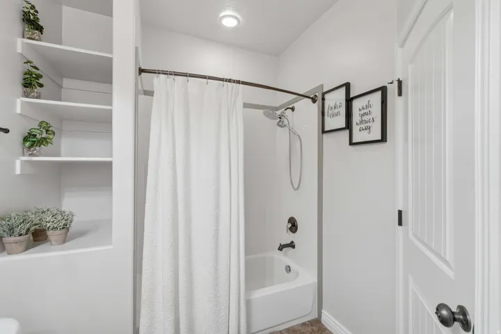 Built-in shelving, tub/shower combination, recessed lighting, panel door, and dark bronze hardware