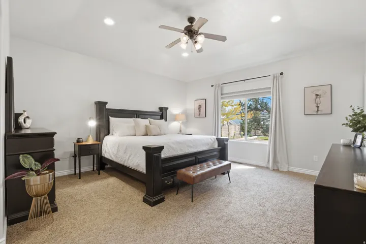 Recessed lighting, ceiling fan light fixture, expansive window, neutral wall paint, and carpeting