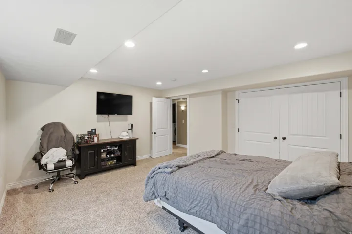 Recessed lighting, wood-finish bi-fold closet doors with black hardware, carpet flooring, and a built-in media console