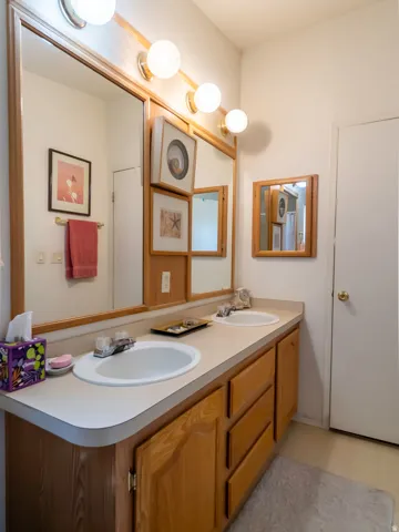 Double vanity with wood-finish cabinetry and integrated sinks, illuminated by a four-bulb fixture