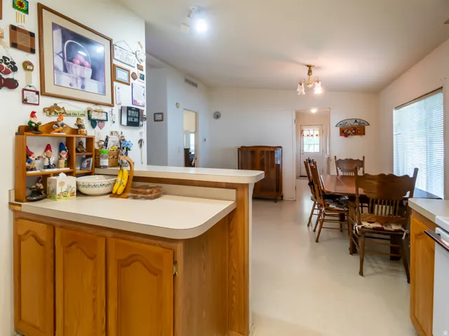 Open-concept kitchen and dining area featuring a breakfast bar with wood-finish cabinetry, light-toned countertops, and neutral flooring
