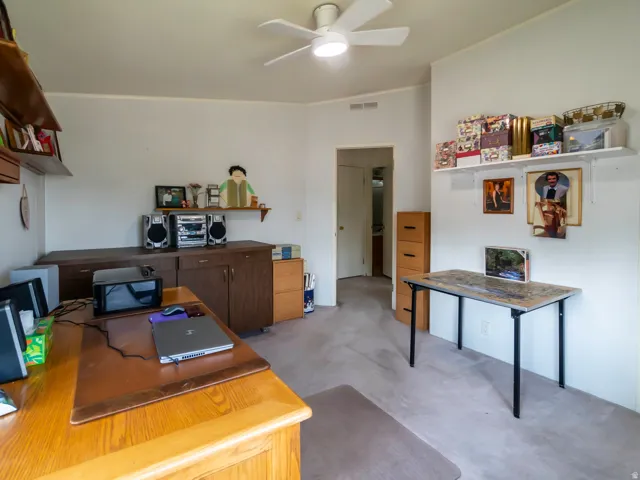 Flexible room featuring carpet flooring, built-in shelving, and a ceiling fan with integrated lighting