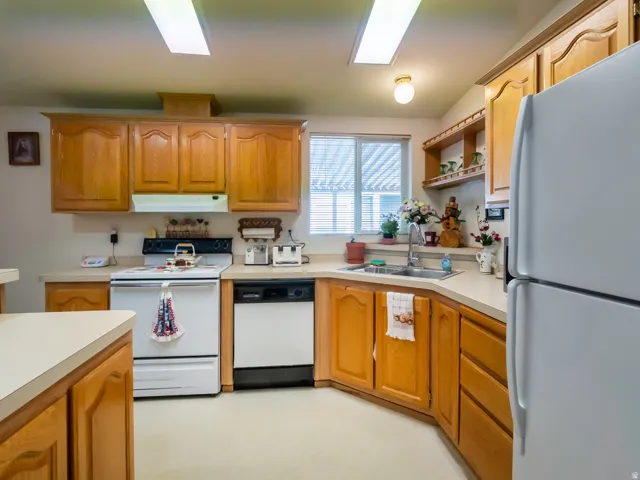 Kitchen featuring wood-finish cabinetry, light-toned countertops, and a full suite of white appliances