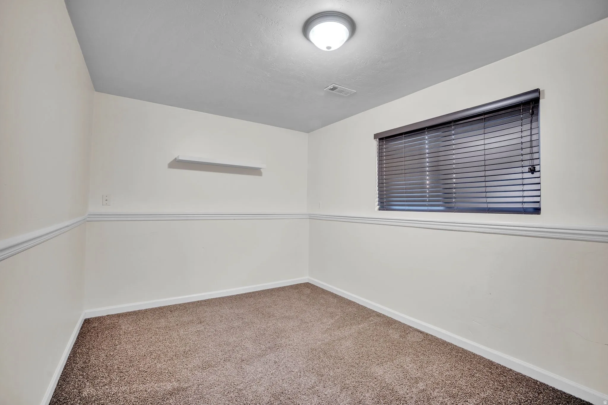 Neutral wall finishes with a ceiling-mounted light fixture