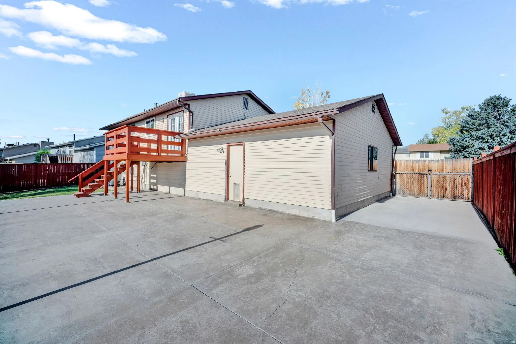 Expansive concrete patio with a wooden deck featuring wood railings and stairs