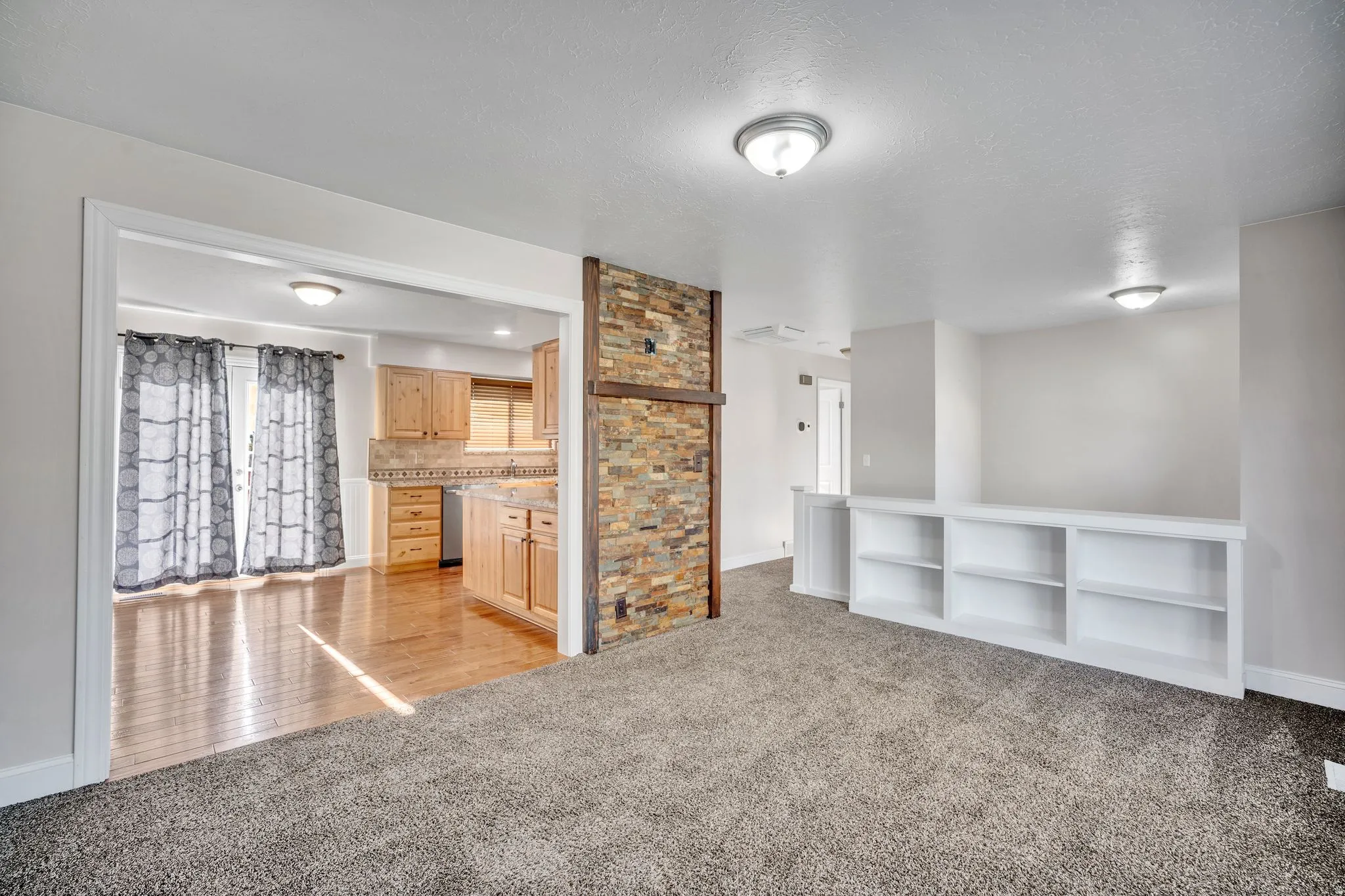 Living area with built-in shelving, carpet flooring, and a stone accent wall