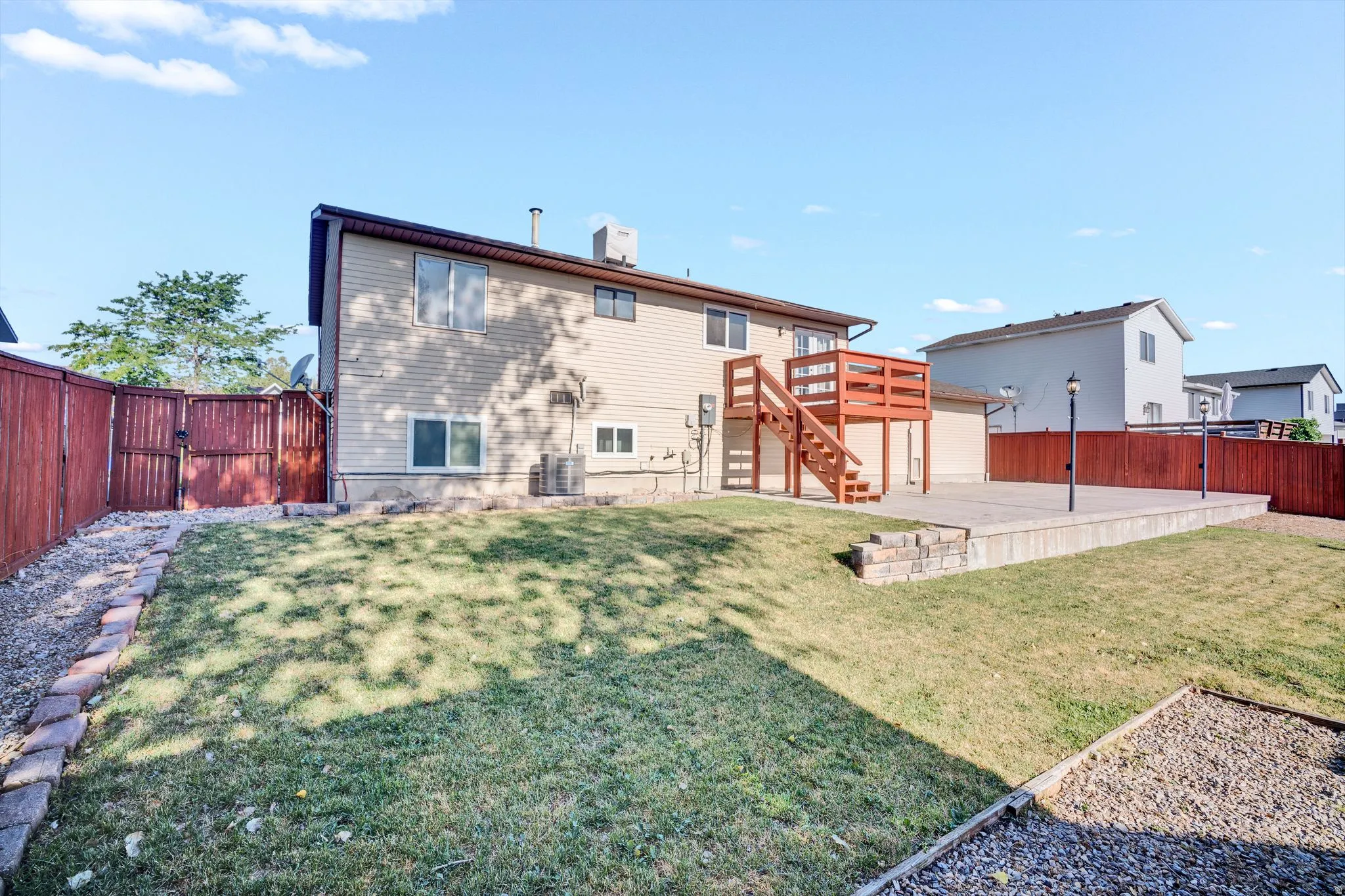 Expansive backyard featuring a multi-level wood deck with stairs, a large paver patio, and a sloped lawn